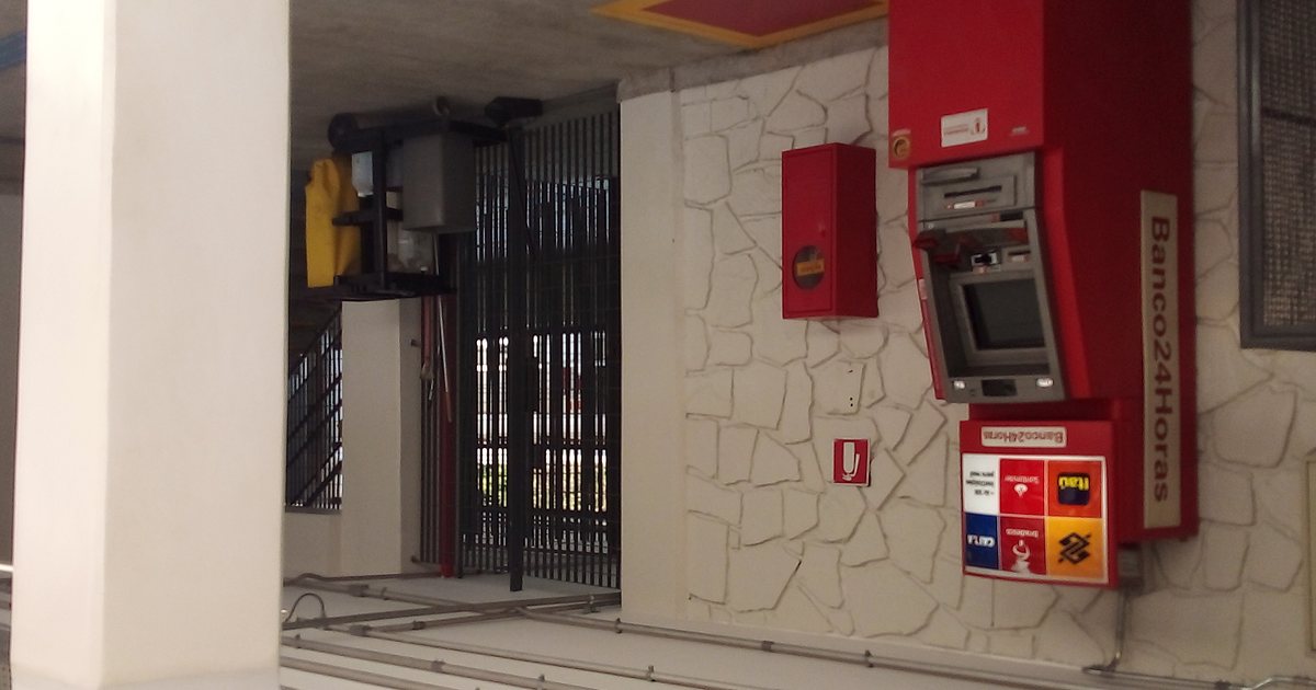 A Banco24Horas cash machine set into the outside wall of a shop, beside a metal gate