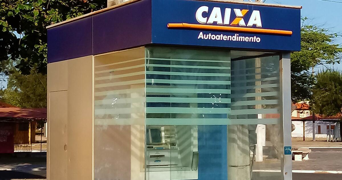 A Caixa self-service ATM kiosk at a bus station in Luís Correia, Piauí, its blue sign reading CAIXA Autoatendimento over a glass booth with the machine inside