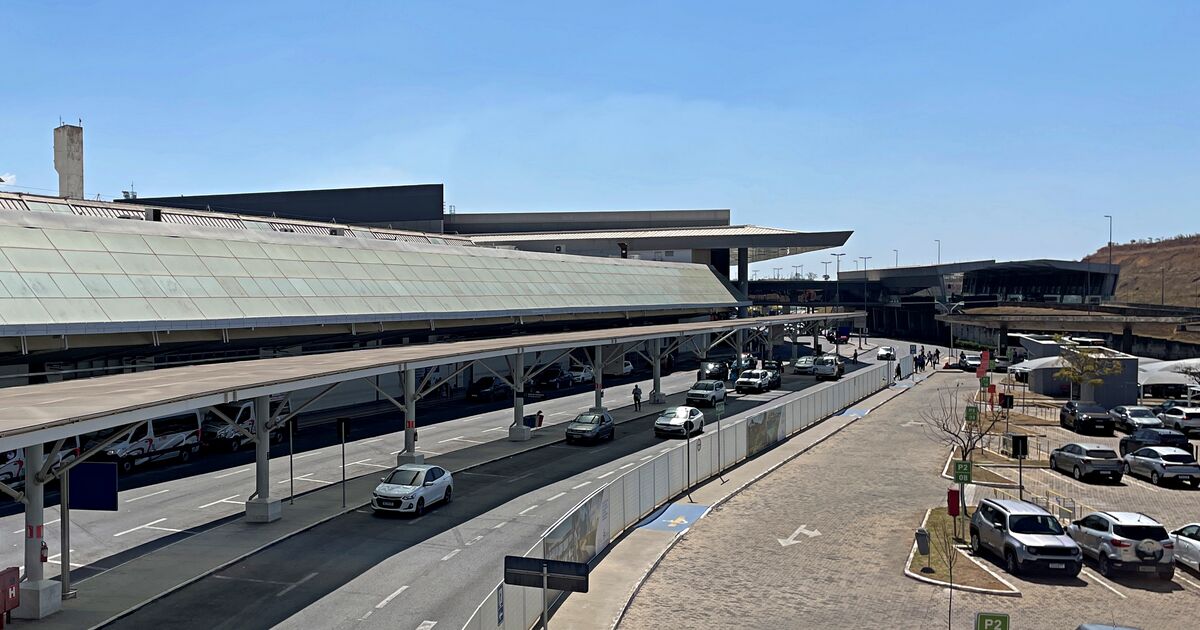 Terminal 1 at Belo Horizonte-Confins airport in September 2025, seen from the P2 parking lot: the glass roof, the covered curbside and the access road