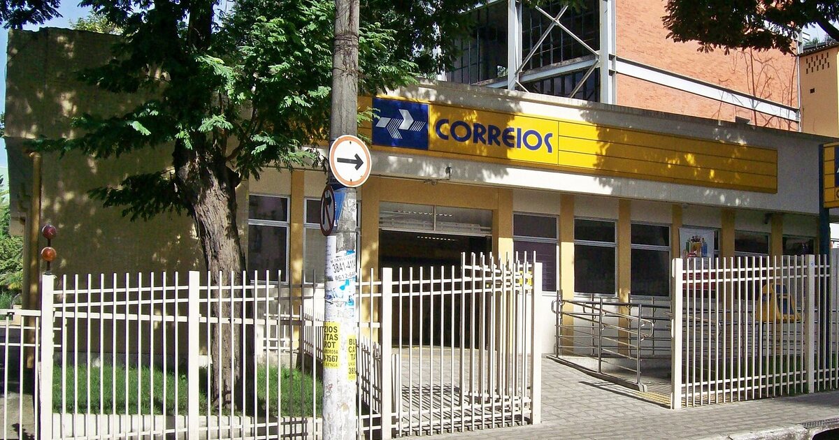 A yellow Correios post office on a Brazilian street corner, seen from across the road