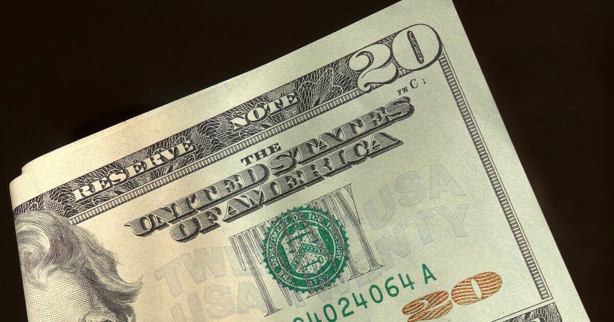 Close-up of a folded United States twenty-dollar note resting on another, against a dark background