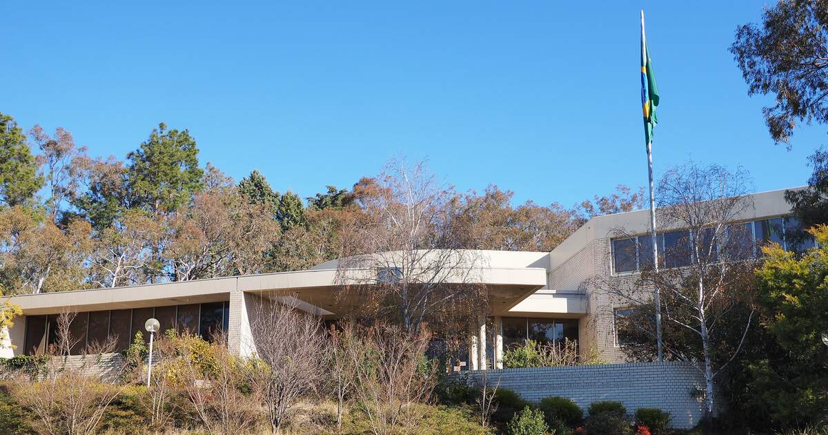 The Embassy of Brazil in Canberra in July 2014: a low pale-brick building behind a winter garden, the Brazilian flag on a tall pole against a clear sky