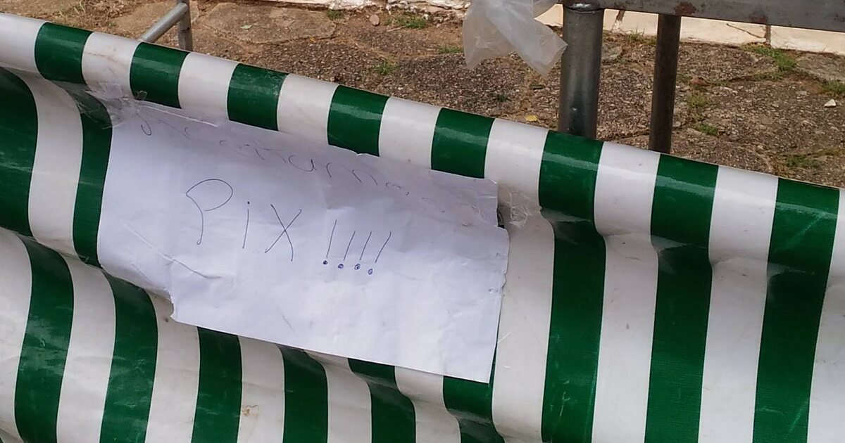 A handwritten paper sign reading PIX taped to the green-and-white striped skirt of a Brazilian street market stall