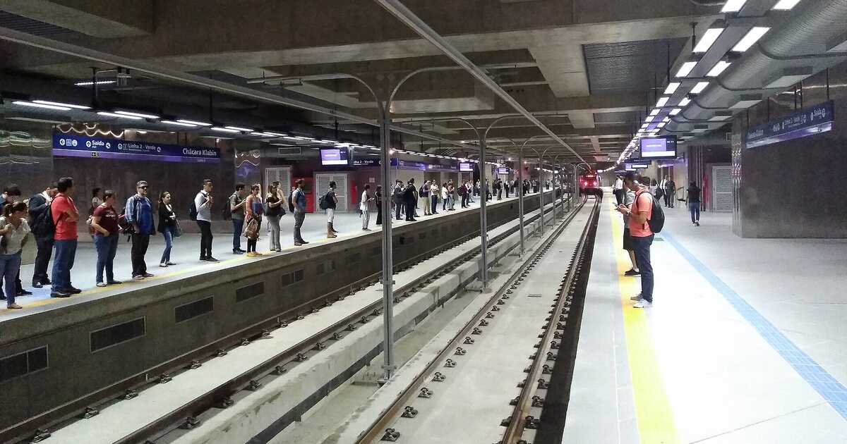 A São Paulo metro platform with passengers waiting on the far side, track and lighting running into the distance
